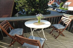 A balcony with a round table and two wooden chairs with patterned cushions. - Angelika's holiday apartment Prerow (Prerow)