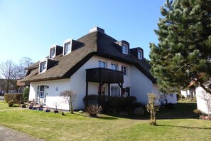 A two-story house with a steeply pitched roof, a front porch, and a well-maintained lawn. - Angelika's holiday apartment Prerow (Prerow)