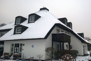 Ein zweistöckiges Haus mit verschneitem Dach und einem sichtbaren 'G' Schild an der Vorderseite.
