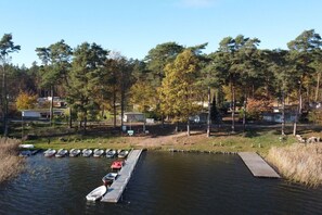 A dock with boats, a small pier, and a forested area with cabins in the background. - Holiday park in Lychen with swimming pool (Lychen)