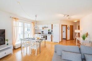 Een modern appartement met een eethoek, kitchenette en een woonkamer met een bank.