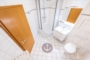Et badeværelse med bruser, toilet og håndvask.