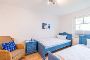 A bedroom with two beds, a nightstand, a chair, and a painting on the wall. - Holiday apartment with 2 bedrooms (Juliusruh)
