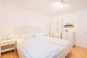 Um quarto com cama, mesa de cabeceira, cômoda e espelho.