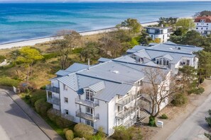Zona residencial costeira com casas modernas, uma praia e vista clara para o mar.