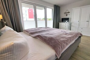 A hotel room with a bed, a television, a wardrobe, and a window with curtains. - Holiday apartment in Glowe with swimming pool (Glowe)
