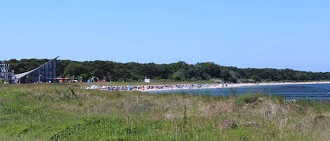 En strand med en modern byggnad i bakgrunden.