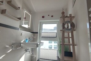 A bathroom with a mirror, sink, and a window with blinds. - Holiday apartment in Glowe with swimming pool (Glowe)