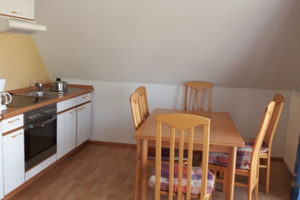 A compact kitchen with a stove, sink, and wooden dining table with chairs.