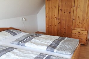 A bedroom with a bed, wooden wardrobe, and a bedside lamp. - Holiday apartment in Breege with Wi-Fi (Breege)