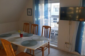 A dining area with a table set for four, chairs, a small plant, and a television mounted on the wall. - Holiday apartment in Breege with Wi-Fi (Breege)