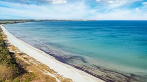 Paisatge costaner amb una platja sorrenca i mar blau clar.