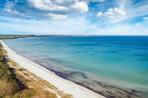 Een kustlandschap met een zandstrand en een heldere blauwe zee.