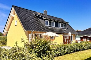 Una casa groga amb teulada fosca, una finestra petita i una porta.
