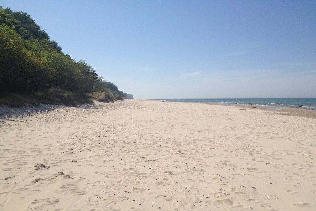 A wide sandy beach with footprints and a clear sky.