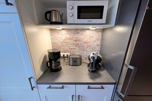 A compact kitchen with a microwave, toaster, coffee maker, and kettle. - Holiday home in Rügen with 1 bedroom (Dranske-Lancken)
