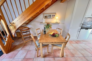 A dining area with a wooden table, chairs, a fruit bowl, and a vase of flowers. - Holiday home in Rügen with 1 bedroom (Dranske-Lancken)