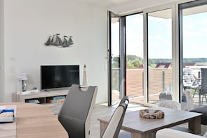 A modern living room with a flat-screen TV, a dining table, and a sofa. - The sea is always a good idea! (Glowe)