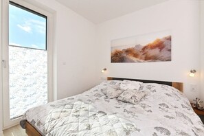 Ett sovrum med en säng, ett fönster med utsikt och en tavla på väggen.