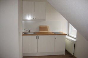 A small kitchenette with white cabinets, a wooden countertop, a sink, and a window. - Country House Lake District 2 (Lychen)