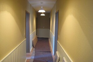 A narrow hallway with a carpeted floor, white baseboards, and a ceiling light fixture. - Country House Lake District 2 (Lychen)