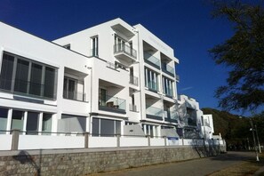 Een modern wit gebouw met meerdere balkons en grote ramen.