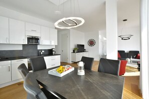 Een moderne keuken met witte kasten, een zwart aanrecht en een eethoek met een tafel voor twee personen.