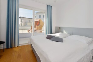 Een hotelkamer met een groot bed, uitzicht door een schuifdeur en een balkon met een stoel.