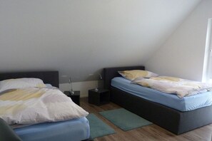 Ein Schlafzimmer mit zwei Betten, einem Nachttisch, einer Lampe und einem Fenster.