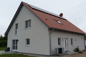 Ein zweistöckiges Haus mit einem geneigten Dach, einer Satellitenschüssel und einer Klimaanlage.
