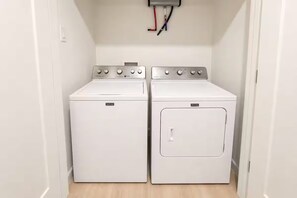 Un cuarto de lavandería con dos lavadoras de tambor frontal blancas y un enchufe eléctrico en la pared.