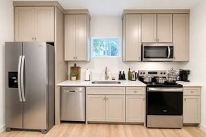 Una cocina moderna con electrodomésticos de acero inoxidable, lavavajillas y armarios de tonos claros.