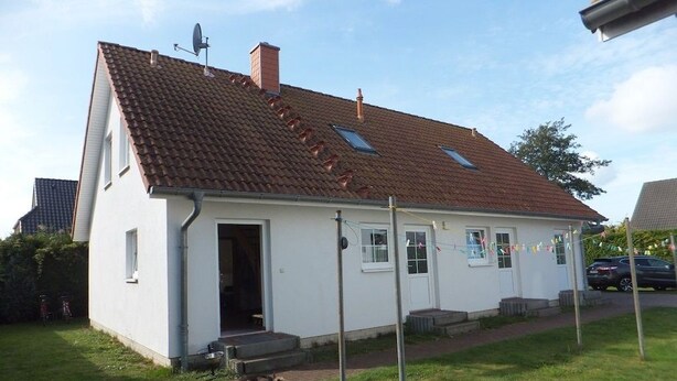 Yhden kerroksen talo, jossa on kalteva katto, satelliittiantenni ja pieni kuisti.