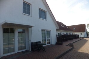 A two-story building with a patio area, a covered seating area, and a staircase leading to the upper floor. - 2 in Vanessa's house (Zingsst)
