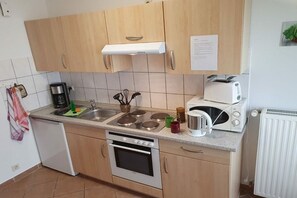 Cozinha com armários de madeira, forno embutido, micro-ondas, torradeira e cafeteira.