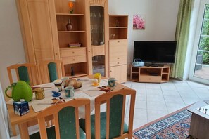 A dining area with a table set for two, a television, and a bookshelf. - 2 in Vanessa's house (Zingsst)