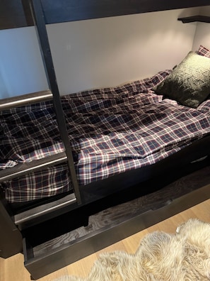Ein Etagenbett mit karierter Bettdecke und einem Kissen.