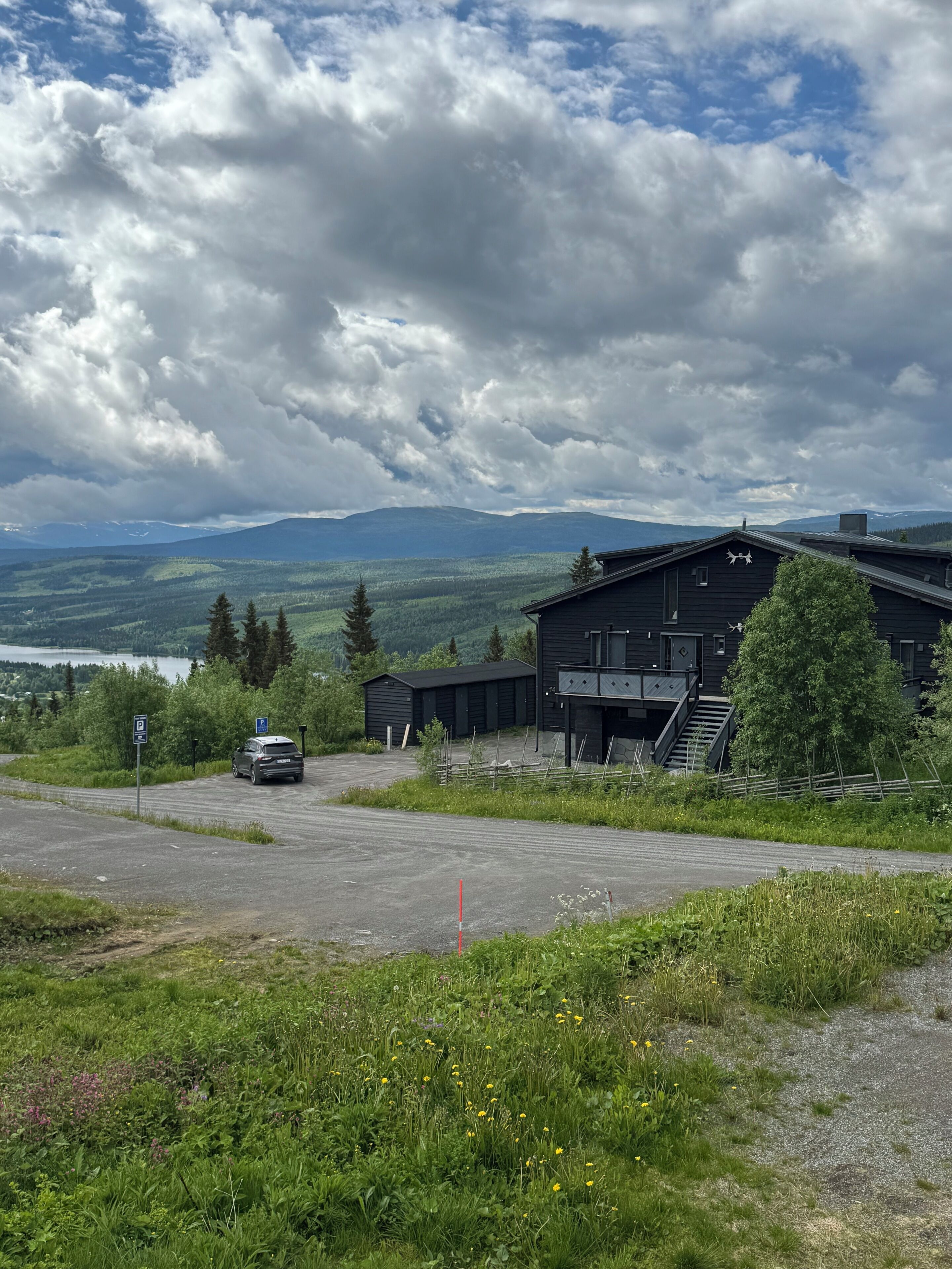 Ein Gebäude mit Parkplatz und Bergblick.