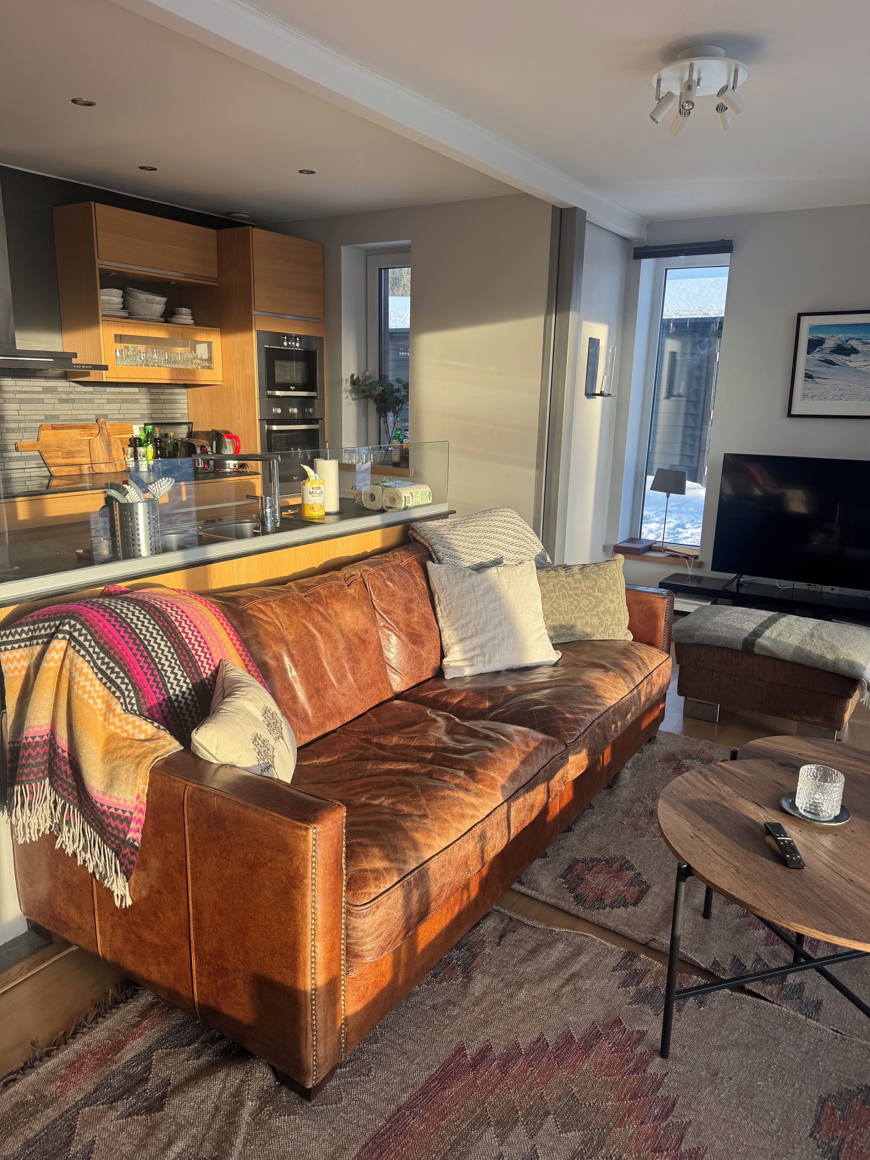 Ein modernes Wohnzimmer mit einer Ledersofa, einem Couchtisch und einem Fernseher.