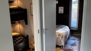 Een slaapkamer met een bed, een raam en een deur naar een andere kamer.
