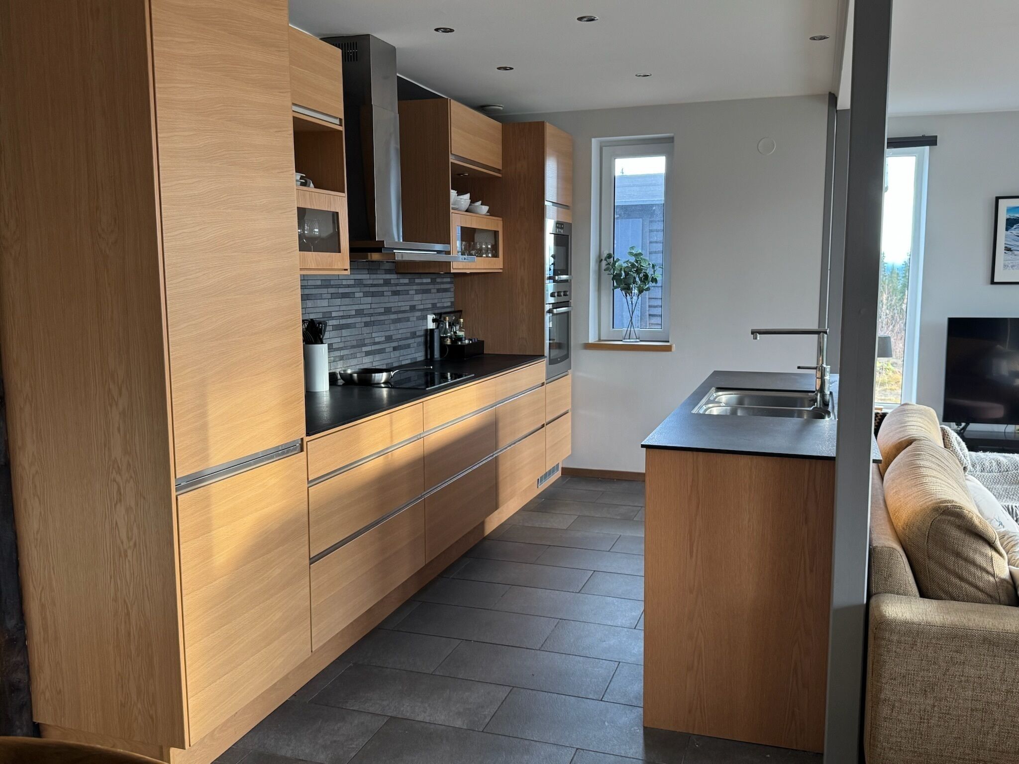 A modern kitchen with wooden cabinets, a black countertop, and stainless steel appliances.