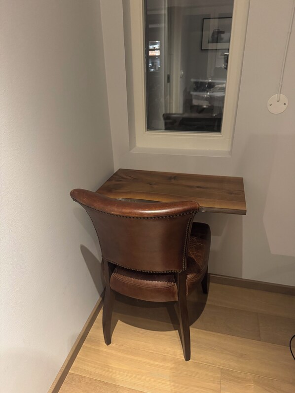 A corner room with a wooden table and a brown leather chair.