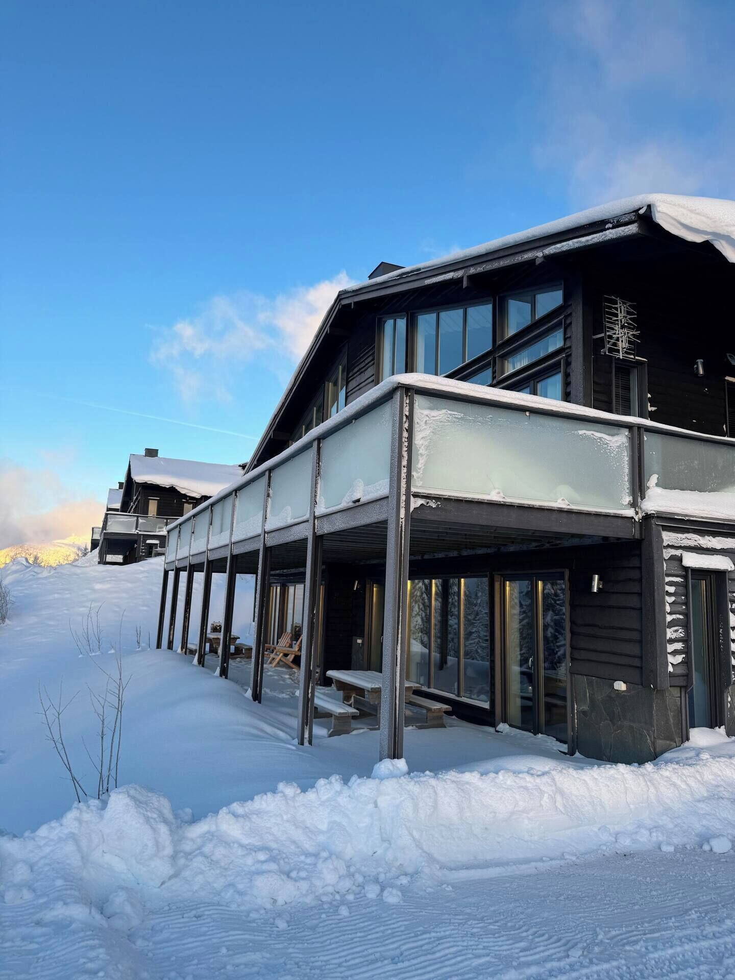En modern byggnad med ett takförsett utomhusområde, omgiven av snö.