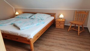 A bedroom with a wooden bed, bedside tables, and a chair. - 5 in the Damaris house (Zingst)