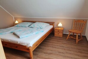 A bedroom with a wooden bed, bedside tables, and a chair. - 5 in the Damaris house (Zingst)