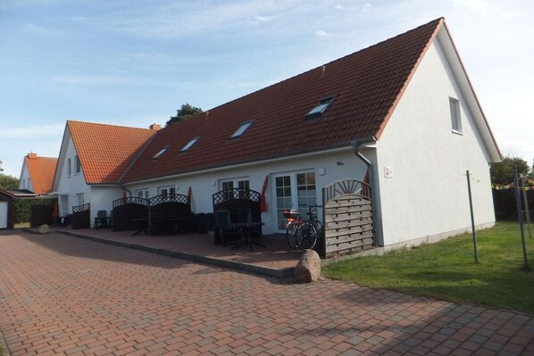 A two-story house with a red-tiled roof, a paved driveway, and a front porch with outdoor furniture. - 5 in the Damaris house (Zingst)