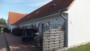 A building with a tiled roof, a gated entrance, and outdoor seating. - 5 in the Damaris house (Zingst)