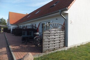 A building with a tiled roof, a gated entrance, and outdoor seating. - 5 in the Damaris house (Zingst)