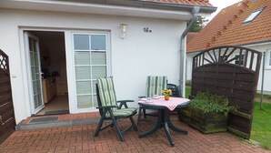 A patio with two chairs and a table, a door leading to a garage, and a number '16' on the wall. - 5 in the Damaris house (Zingst)