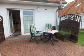 A patio with two chairs and a table, a door leading to a garage, and a number '16' on the wall. - 5 in the Damaris house (Zingst)